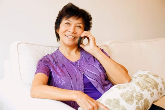 Close-up of a mature woman sitting on a couch and talking on a mobile phone