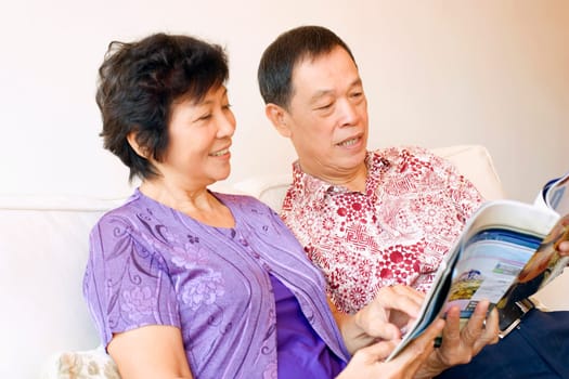 Close-up of a senior man and a mature woman reading a magazine