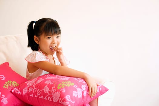 Close-up of a girl sitting on a couch and eating a lollipop