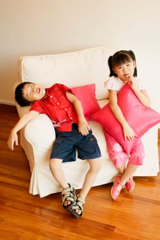 Portrait of a girl sitting on a couch with her brother sleeping beside her