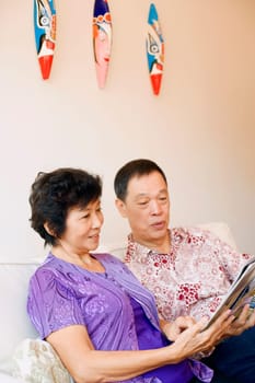 Close-up of a senior man and a mature woman reading a magazine