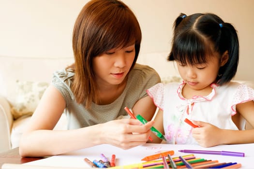 Close-up of a young woman teaching her daughter to color