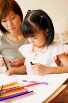 Close-up of a young woman teaching her daughter to color