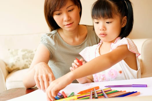 Close-up of a young woman teaching her daughter to color