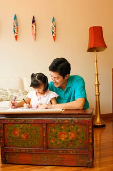 Young man teaching his daughter to color