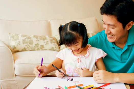 Young man teaching his daughter to color
