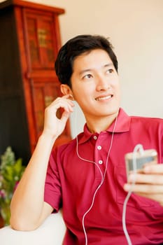 Close-up of a young man listening to an MP3 player and smiling