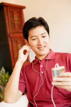 Close-up of a young man listening to an MP3 player and smiling