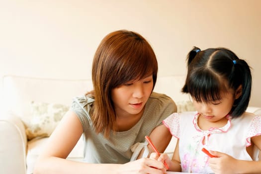 Close-up of a young woman teaching her daughter to color