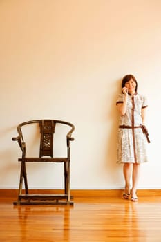 Young woman leaning against a wall and talking on a mobile phone