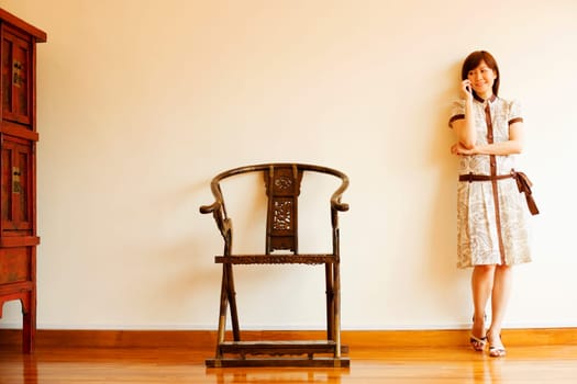 Young woman leaning against a wall and talking on a mobile phone
