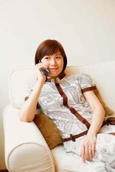 Young woman sitting on a couch and talking on a mobile phone