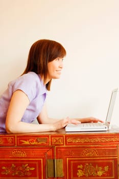 Side profile of a young woman lying on a trunk and using a laptop