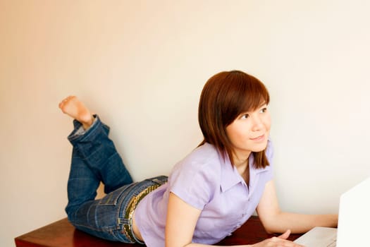 Close-up of a young woman lying on a table and using a laptop