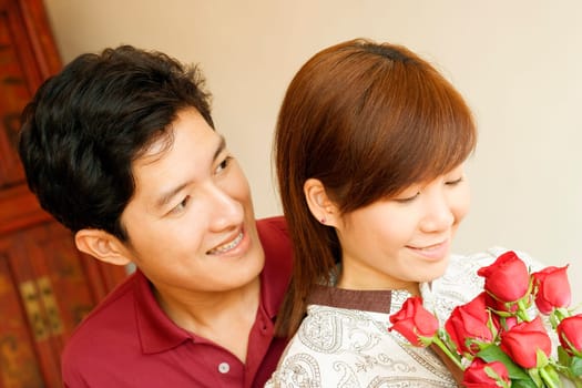 Close-up of a young woman holding flowers with a young man