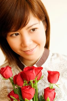 Close-up of a young woman smiling and holding a bouquet of red roses