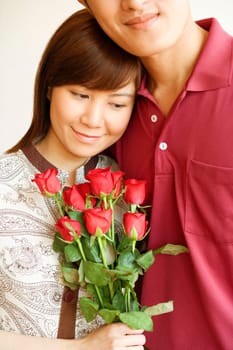 Close-up of a young woman holding a bouquet of red roses and standing with a young man