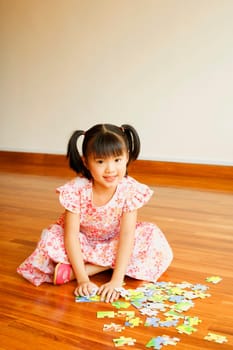 Portrait of a girl smiling and playing with a jigsaw puzzle