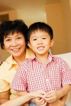 Close-up of a boy smiling and sitting with his grandmother