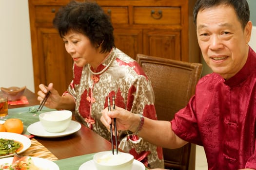 Portrait of a senior man sitting at a dining table with a mature woman beside him