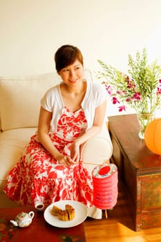High angle view of a young woman sitting on a couch and holding a Chinese lantern