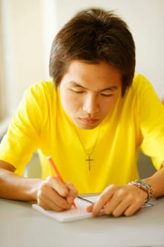 Close-up of a young man writing on a notepad