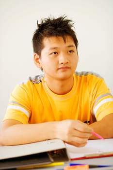 Close-up of a young man holding a pen on a notepad