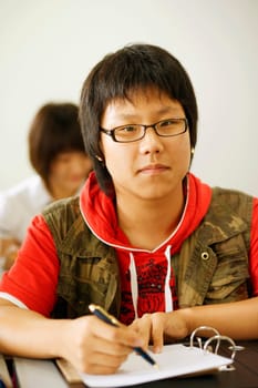 Portrait of a teenage boy holding a pen on a spiral notebook