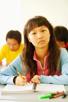 Portrait of a young woman sitting at a desk in the classroom