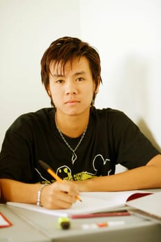 Portrait of a teenage boy holding a pen on a notepad