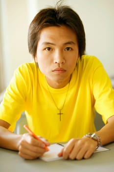 Portrait of a young man holding a pen on a notepad