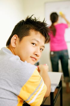 Rear view of a young man sitting in a classroom