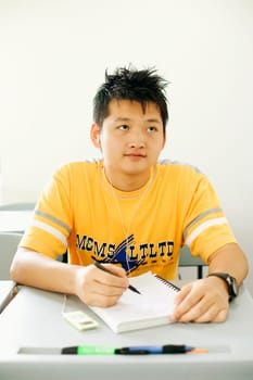 Young man sitting in the classroom and listening to an MP3 player