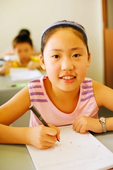 Portrait of a girl holding a pen on a notepad in the classroom