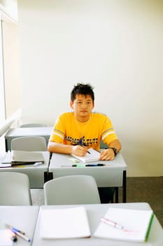 Portrait of a young man writing on a notepad in the classroom