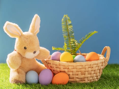 Easter bunny toy and Easter eggs in basket on green grass
