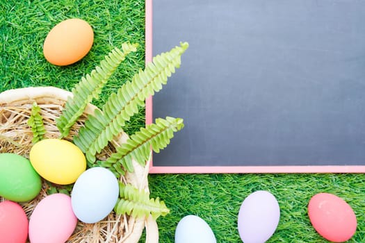 Close up Colorful easter eggs on green grass and blackboard mockup with copy space