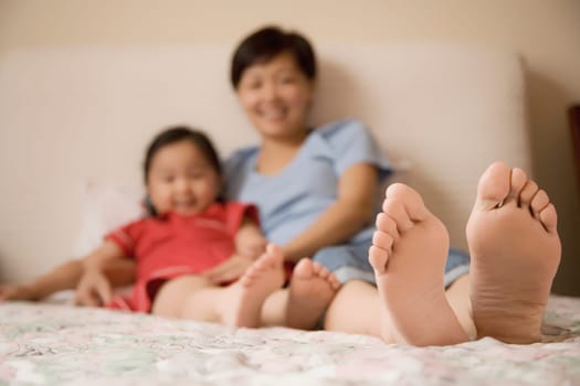 Mid adult woman and her daughter reclining on the bed