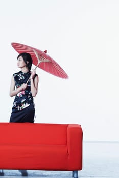 Young woman standing behind a couch holding a parasol