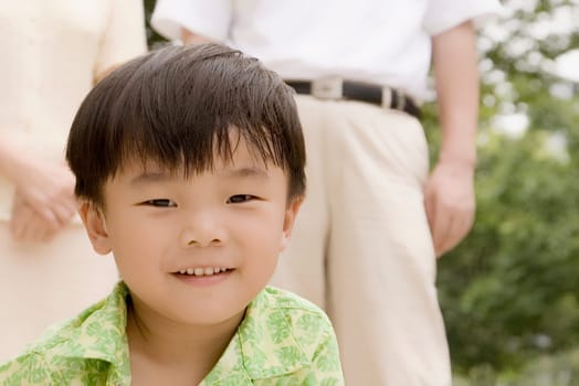 Portrait of a boy smiling with his grandparents standing behind him