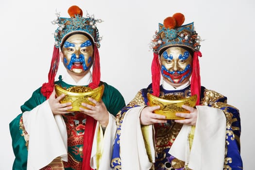 Portrait of two male Chinese opera performers holding bowls full of gold coins
