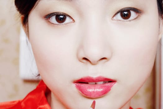 Portrait of a young woman applying lip gloss