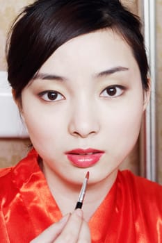 Portrait of a young woman applying lip gloss