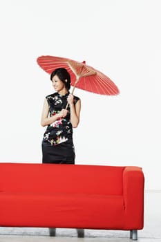 Young woman standing behind a couch holding a parasol
