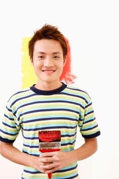 Portrait of a young man holding a paintbrush and smiling