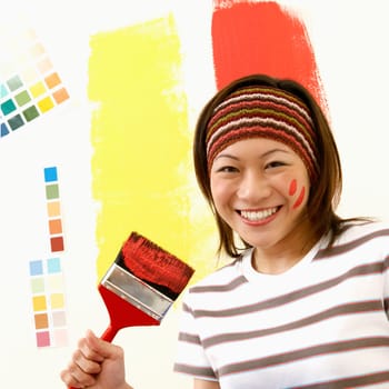 Portrait of a young woman holding a paint tray with a paintbrush
