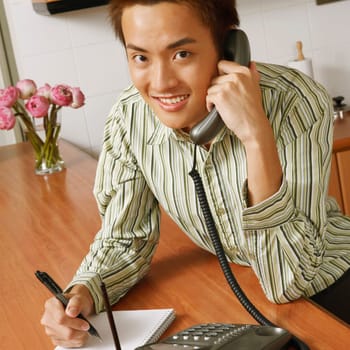 Portrait of a young man using a telephone in the kitchen