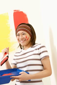 Close-up of a young woman holding a paint tray and a paintbrush