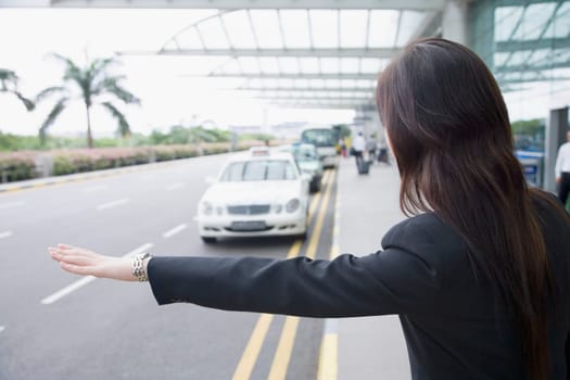 Rear view of a businesswoman hailing a taxi