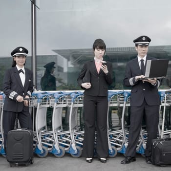 Female cabin crew standing with two pilots at an airport